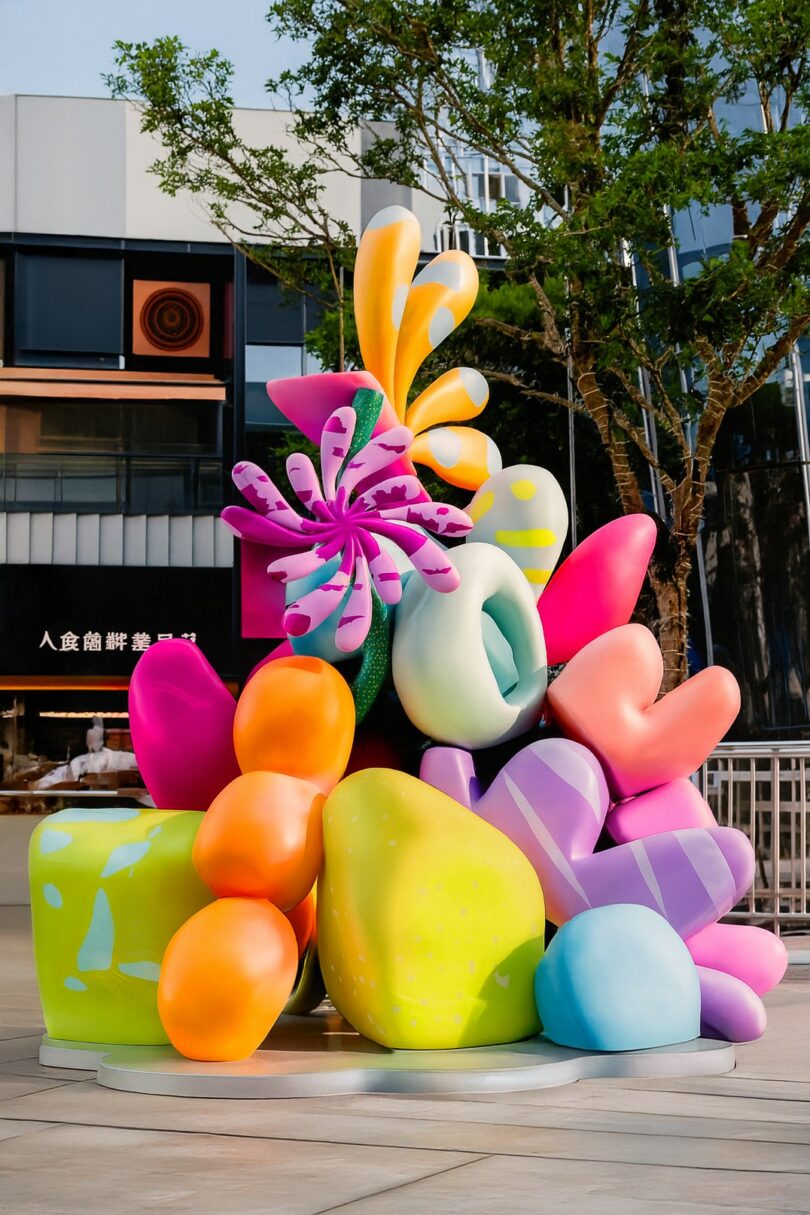 Colorful abstract sculpture with rounded shapes and patterns, resembling oversized coral or organic forms, created by Studio Proba and displayed outdoors in an urban setting