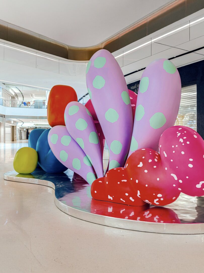 Colorful abstract sculpture by Studio Proba with large, rounded shapes in pink, red, purple, yellow, blue, and green—some adorned with polka dots—displayed in a modern indoor space