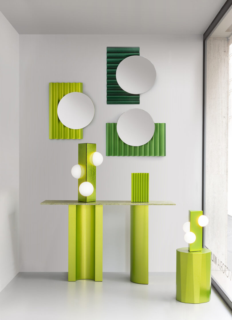 A modern interior features green textured furniture, round mirrors, and sculptural light fixtures with white globes in a minimalist white room.