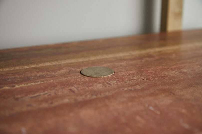 A round wooden plug is set into the surface of a reddish-brown wooden tabletop