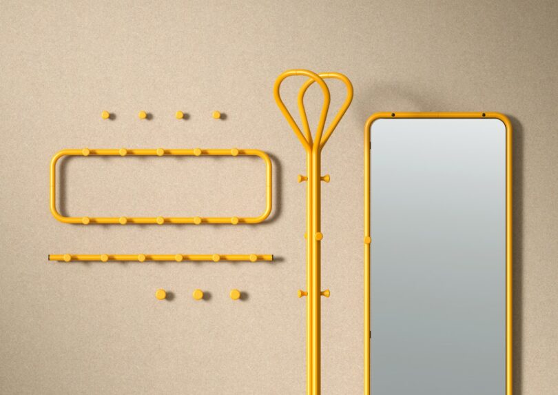 A set of yellow wall hooks, a coat rack, and a tall rectangular mirror are arranged against a beige wall