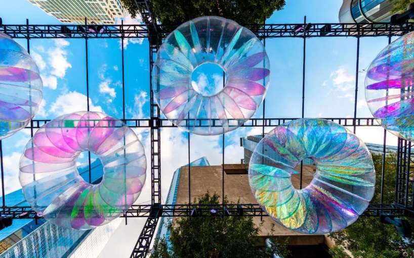 floating oculus installation shimmers in shifting chromatic light above brooklyn's streets