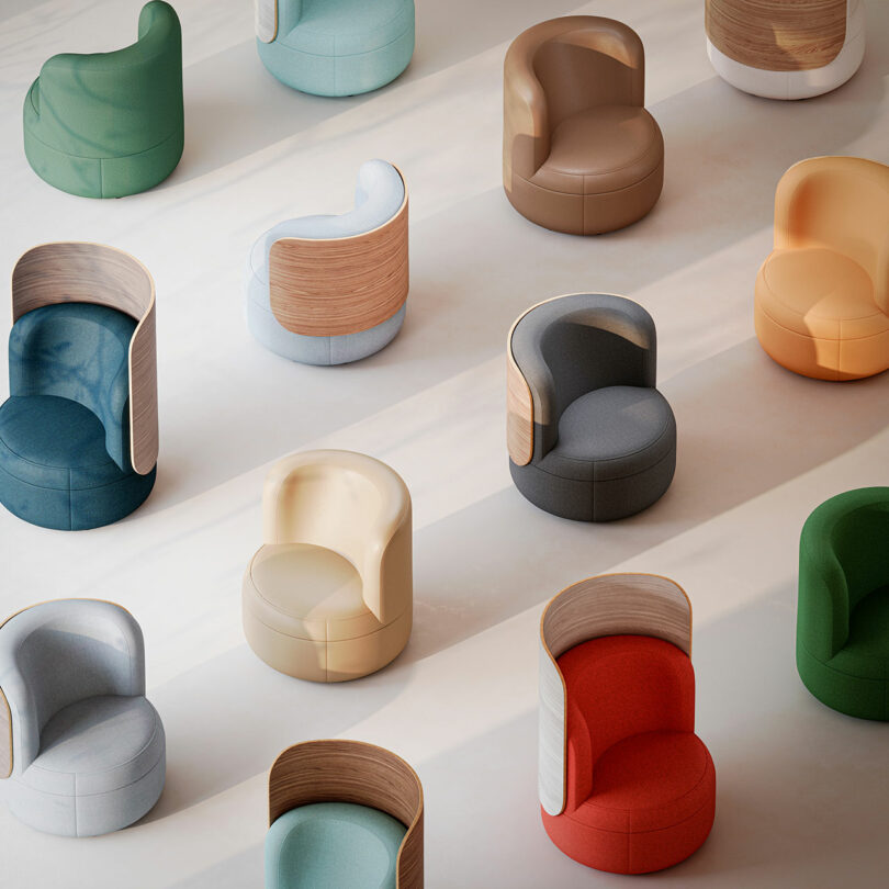 Rows of modern, curved armchairs with wooden backs in various colors are arranged on a light floor, viewed from above.