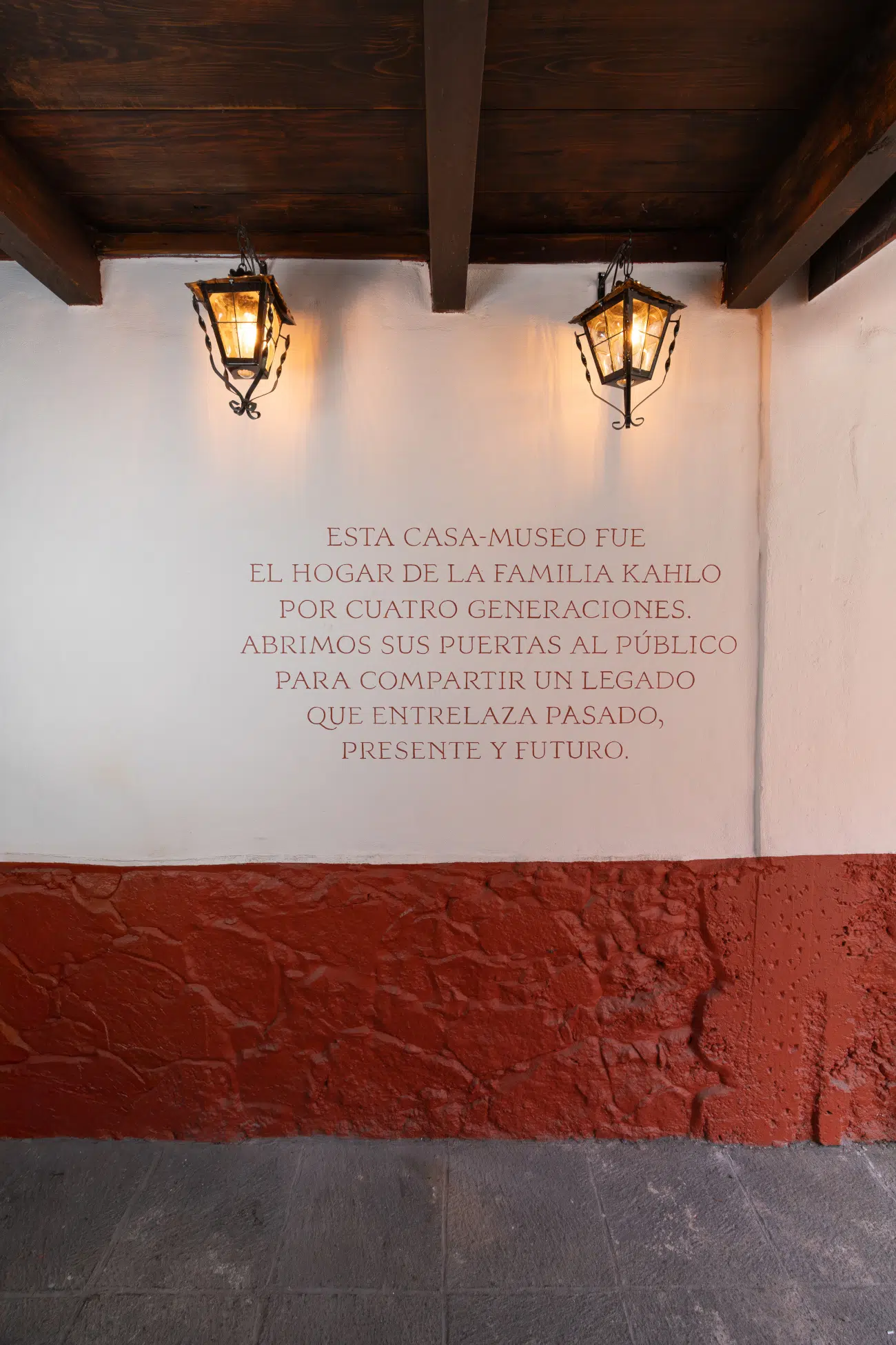 Wall in Museo Casa Kahlo in Mexico City with message in Spanish that reads "This house-museum was the home of the Kahlo family for four generations. We open its doors to the public to share a legacy that weaves past, present, and future."