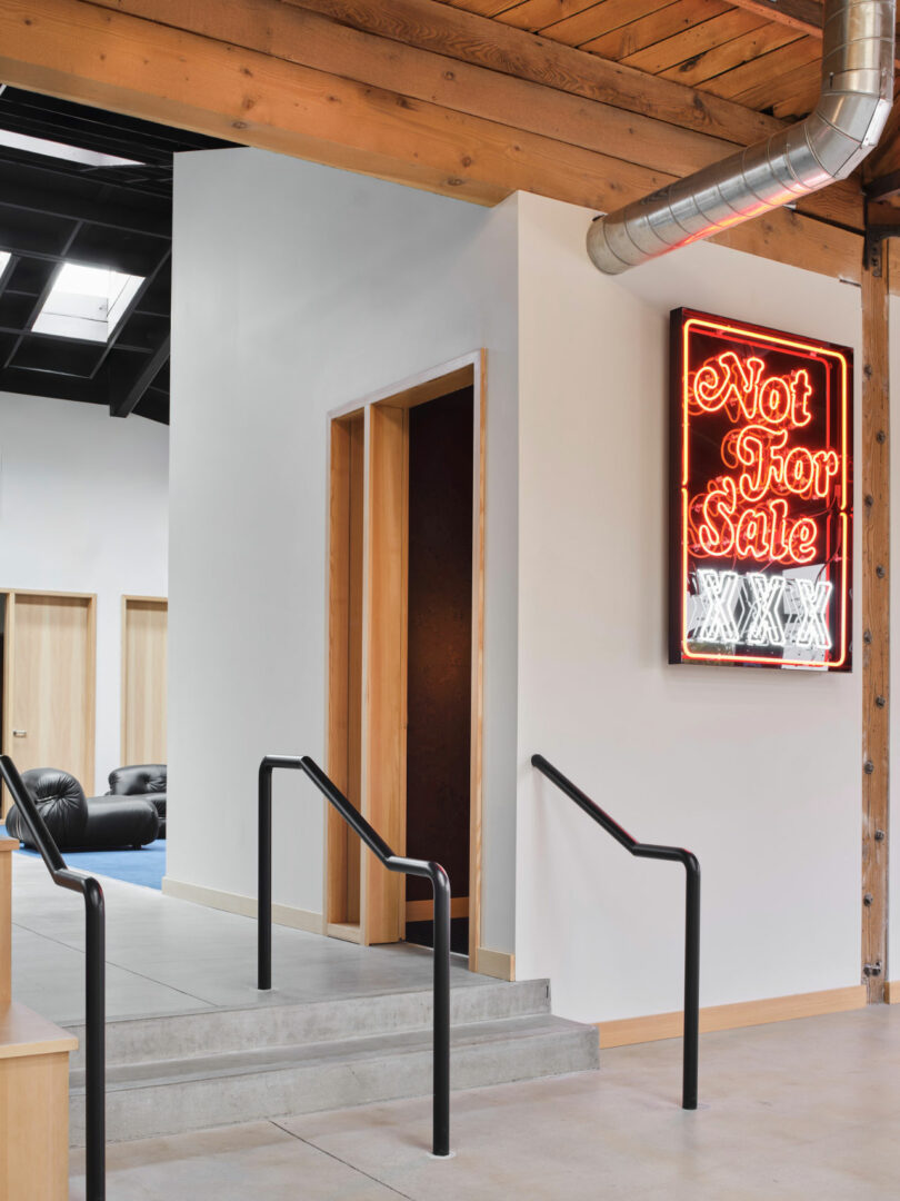 Modern interior with a small ramp and steps leading to a doorway; a neon sign on the wall reads 