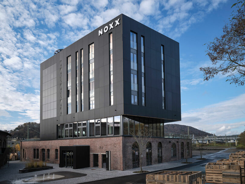 A modern building with a brick lower level and a black upper section labeled 
