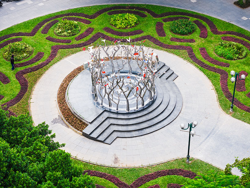a circle of mirroring steel branches composes a luminous forest in hanoi's public realm