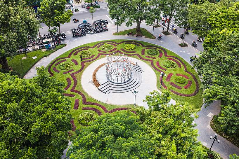 a circle of mirroring steel branches composes a luminous forest in hanoi's public realm