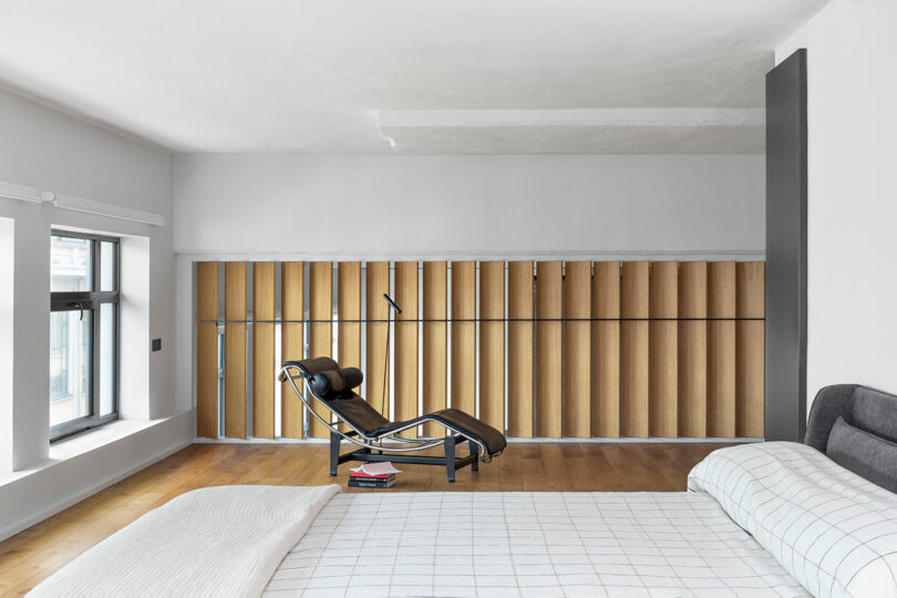 partial side view of modern bedroom with wood detailing and lounge chair