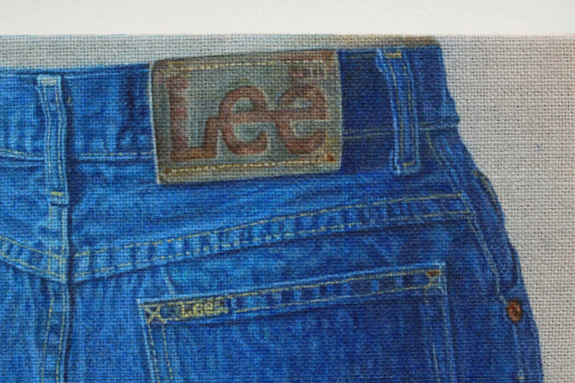 Close-up of the back of blue Lee jeans, showing the stitched brand label on the waistband and a small Lee tag above the pocket.