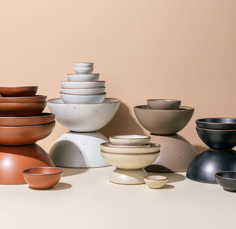 Ceramic bowls in various sizes and neutral tones are stacked and arranged on a beige surface against a tan background, perfect for a Friday Five kitchen refresh.