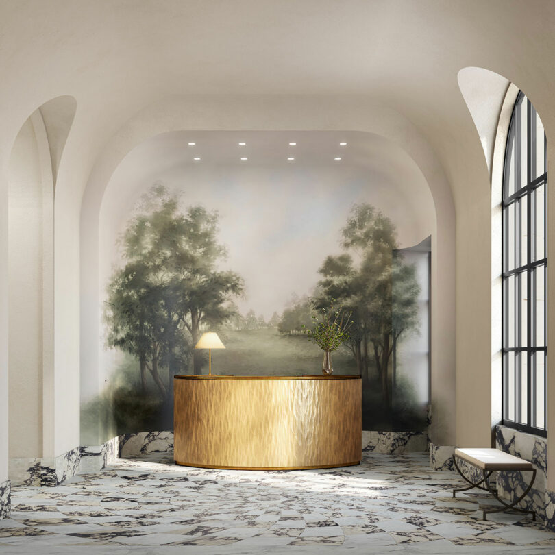 A marble-floored lobby with a gold curved reception desk, a table lamp, and a mural of trees and a landscape on the wall behind—perfect inspiration for this week’s Friday Five. A bench sits beside a large arched window.