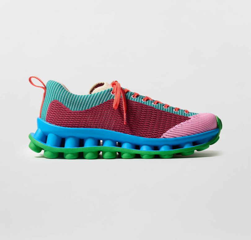 A colorful sneaker with a pink toe, red mesh sides, teal and green upper, blue midsole, and green segmented outsole—showcased in profile on a plain white background—delivers bold 2025 Top 10 Style flair.