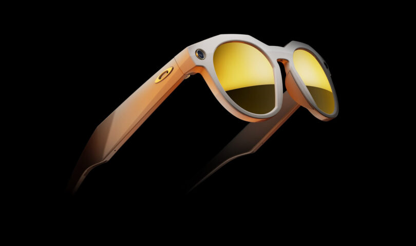 Close-up view of orange Oakley sunglasses with yellow lenses, set against a black background.