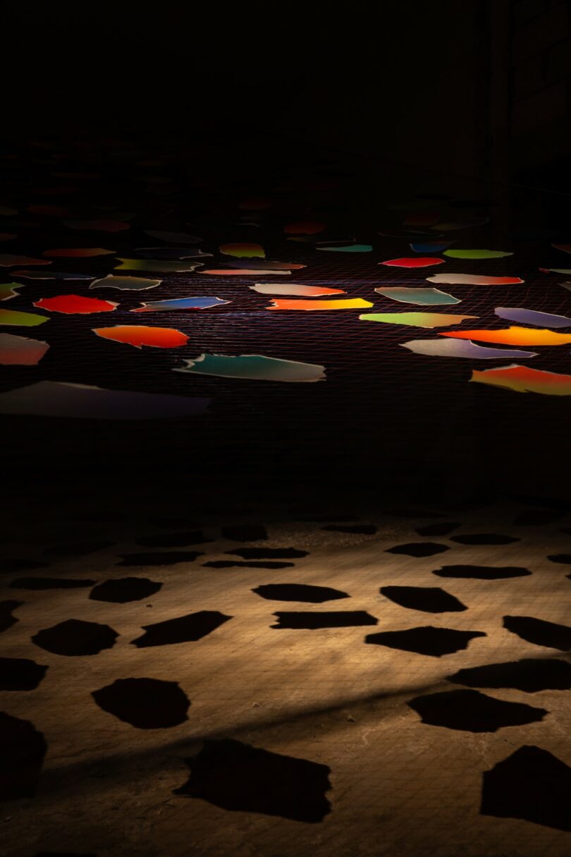 Colorful paper shapes hang from strings indoors,