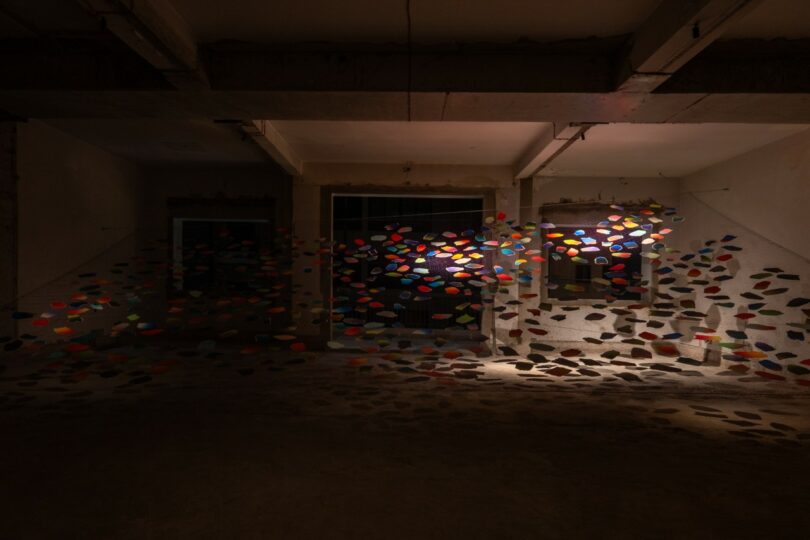 Colorful paper shapes hang from strings indoors,