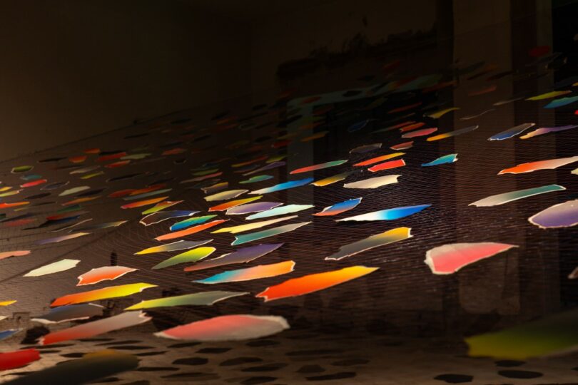 Colorful paper shapes hang from strings indoors,