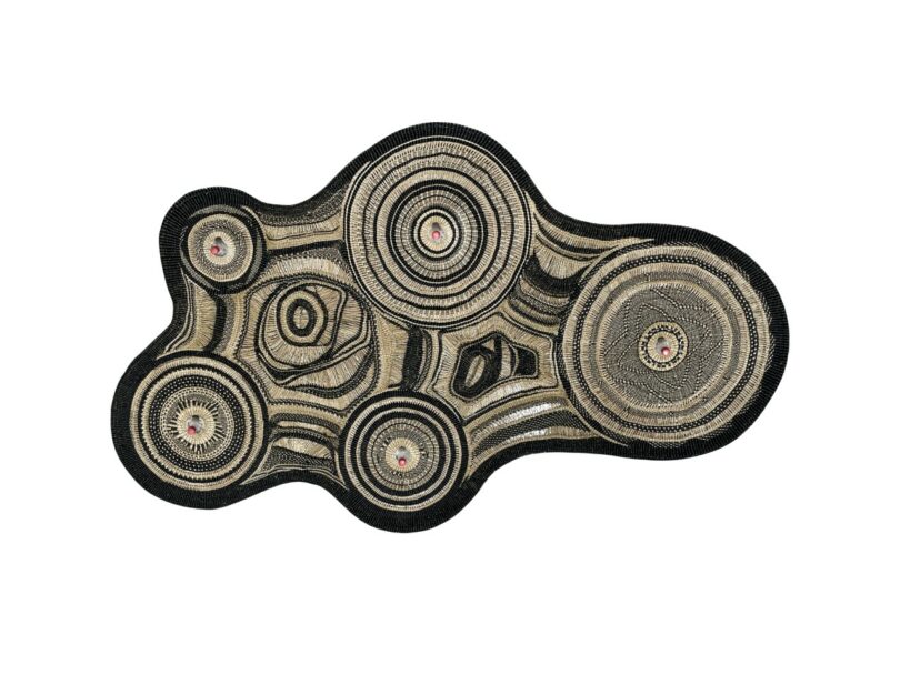 An abstract, irregularly shaped textile-lamp with concentric circular patterns in black, beige, and red tones on a white background