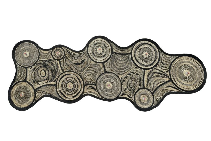 An abstract, irregularly shaped textile-lamp with concentric circular patterns in black and beige on a white background