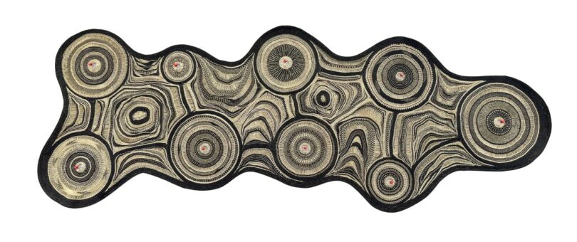 An abstract, irregularly shaped textile-lamp with concentric circular patterns in black and beige on a white background