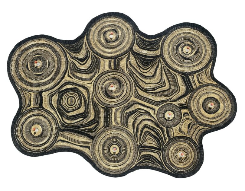 An abstract, irregularly shaped textile-lamp with concentric circular patterns in black and beige on a white background