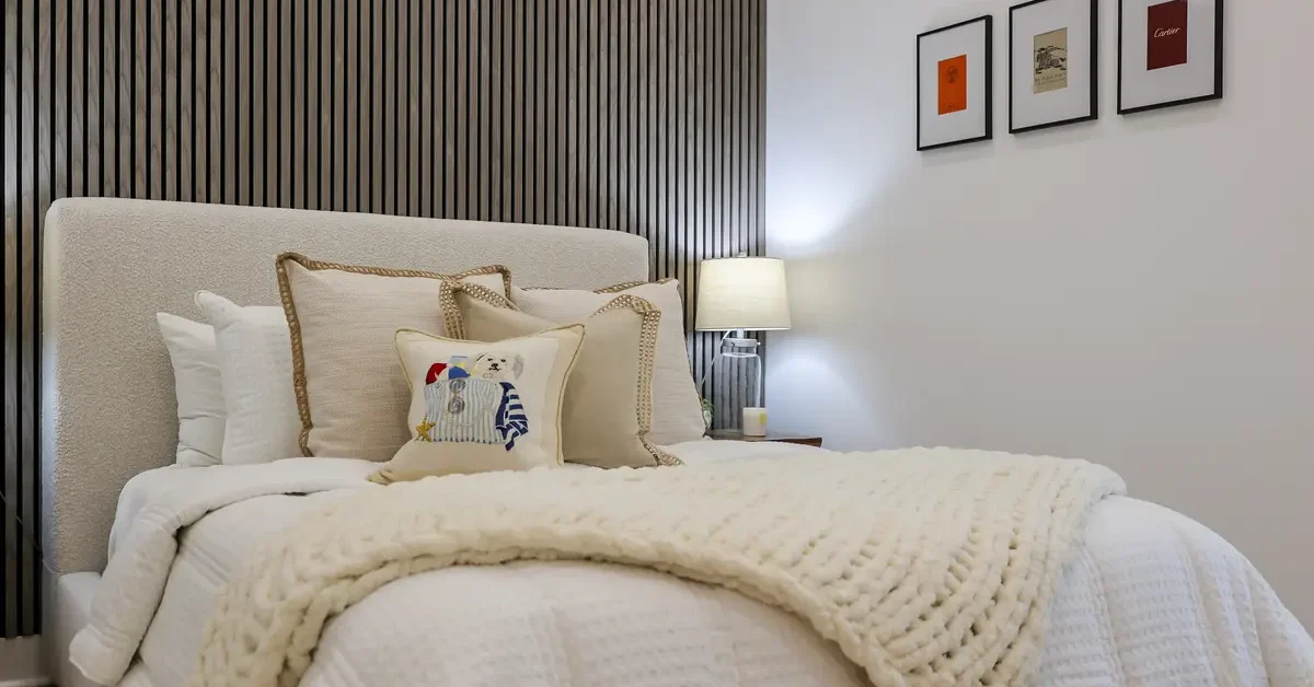 A bedroom decor in off-white with pillows and cushions of various fabrics.