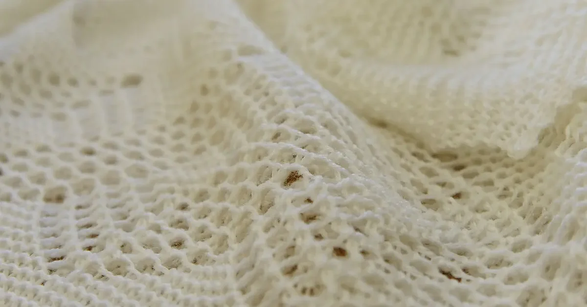 Detail of a cream super-fine merino wool christening shawl.