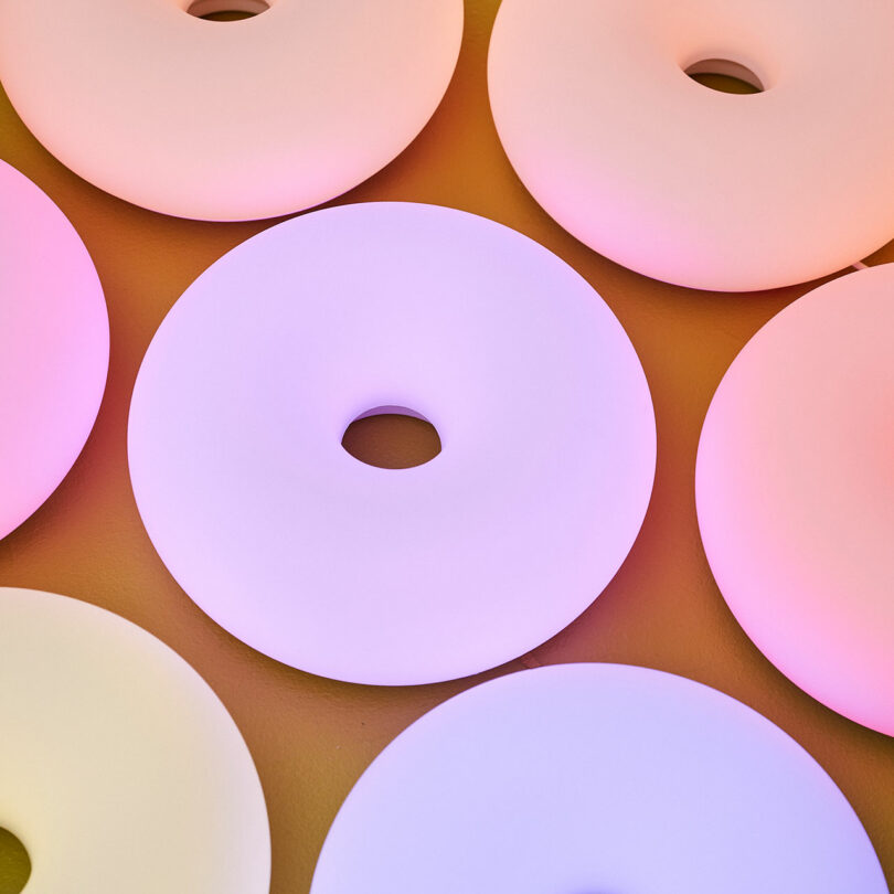 A close-up of several pastel-colored, circular objects with central holes, arranged in a grid pattern on a flat surface.