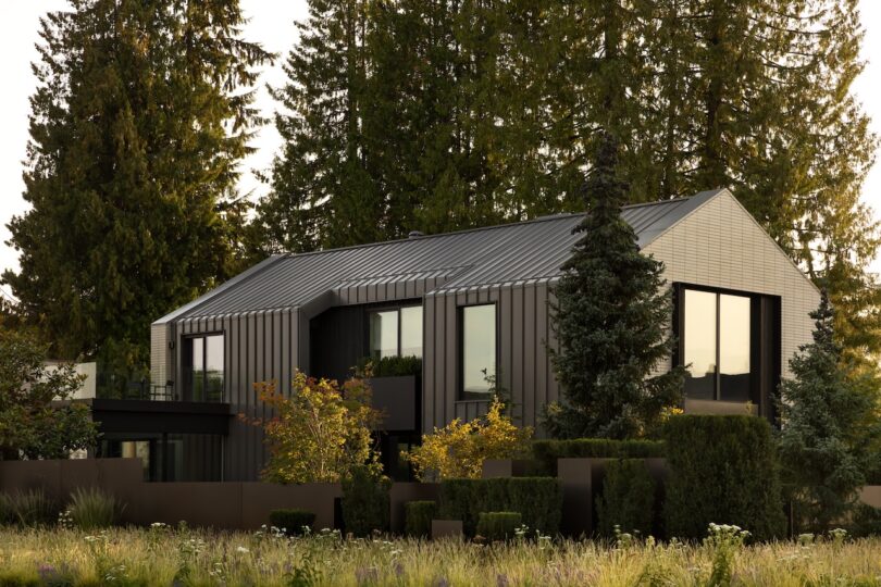 Modern two-story house with dark metal siding and large windows, surrounded by trees and landscaped greenery.