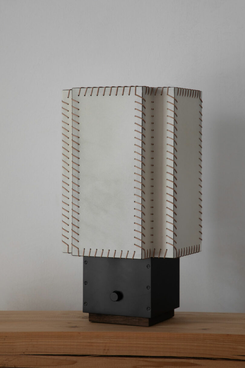Rectangular table lamp with a white stitched shade and a black square base, featured in Friday Five, placed on a wooden surface against a plain white wall.