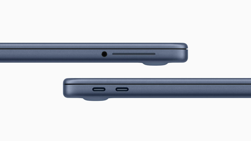 Side view of a blue Apple laptop showing a headphone jack, SD card slot, and two USB-C ports on its thin edges against a white background.