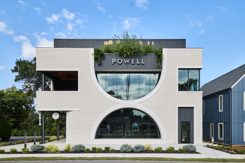 Modern three-story Powell building with a geometric white facade, large arched window, prominent