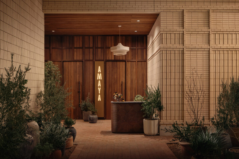 Entrance to Roost Rainey features wooden doors, a lit vertical 