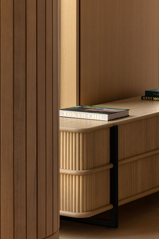 A close-up of a wooden table with vertical grooves, holding two stacked books, one titled 