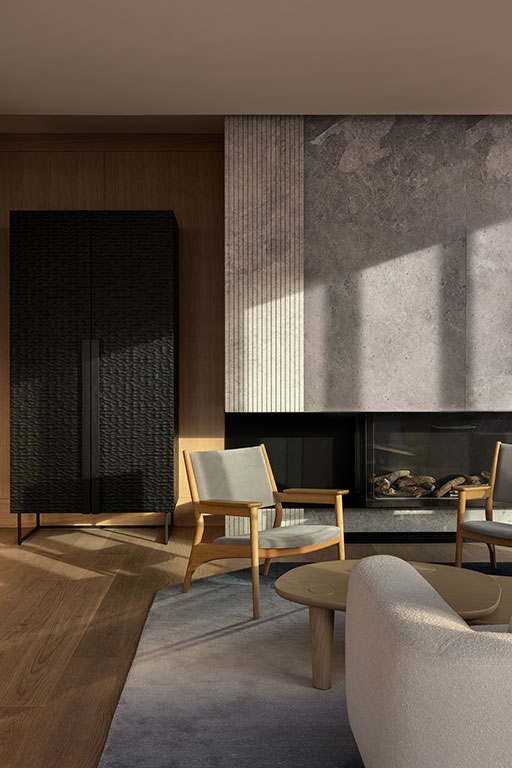 Modern living room with light wood flooring, a black textured cabinet, minimalist chairs, a white sofa, neutral rug, and a fireplace with a stone and wood-paneled wall.