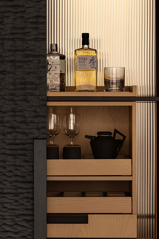 A wooden minibar shelf with a bottle of whisky, a glass, and another bottle on top, wine glasses and a teapot on the middle shelf, and a tray on the bottom shelf.