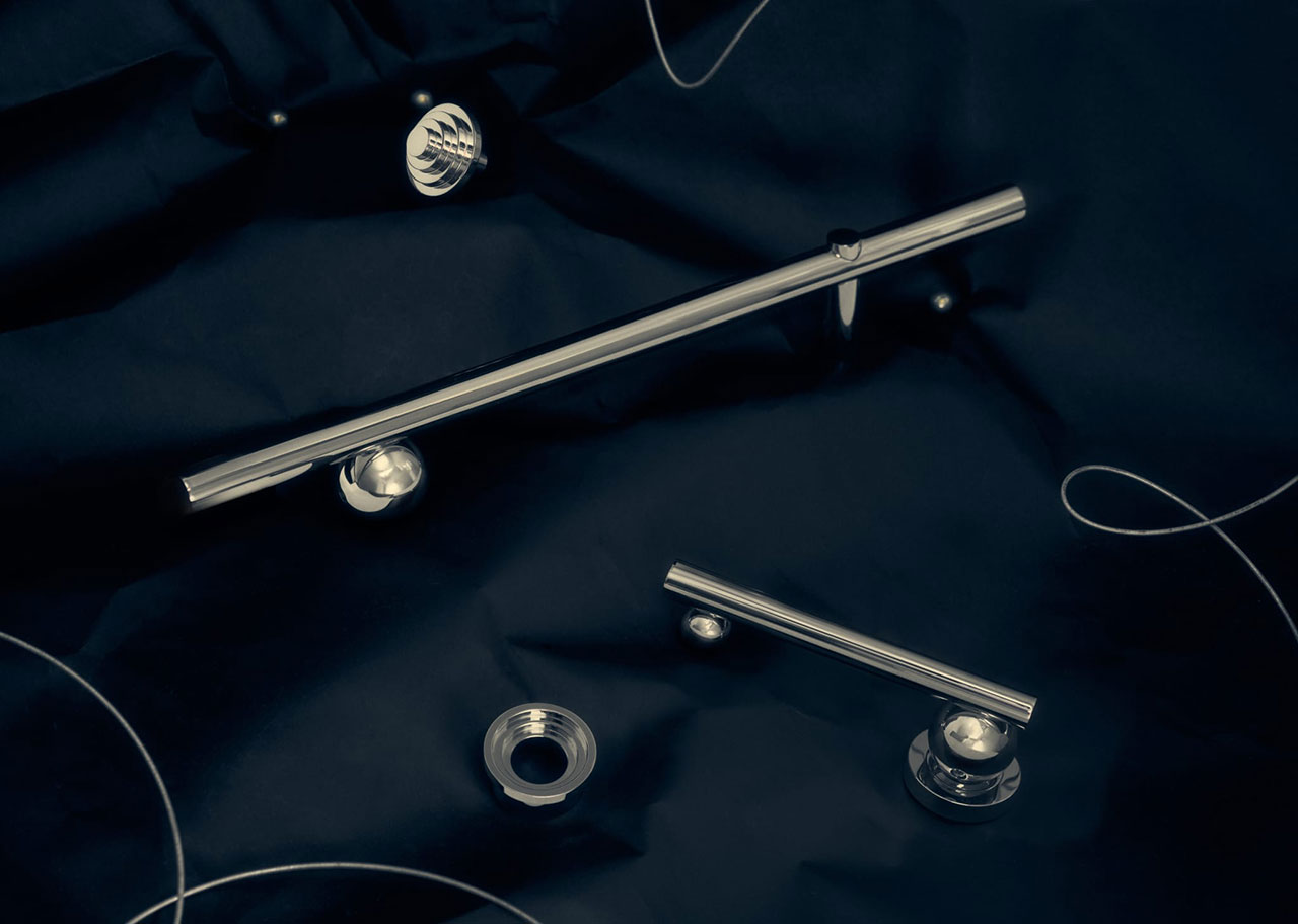 Metal rods and circular hardware pieces are arranged on a dark fabric background, with thin wires loosely scattered around them.