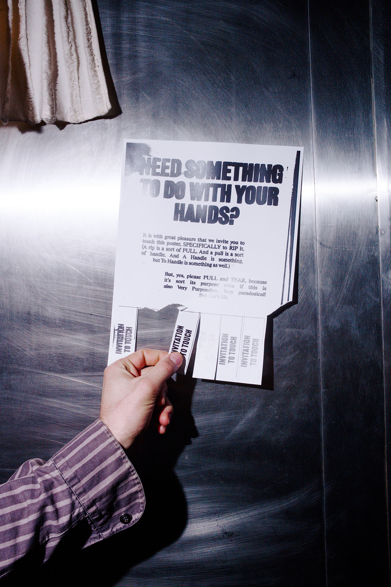 A hand holds a Bankston flyer against a metallic background. The flyer reads, “Need something to do with your hands?” and features tear-off tabs at the bottom.