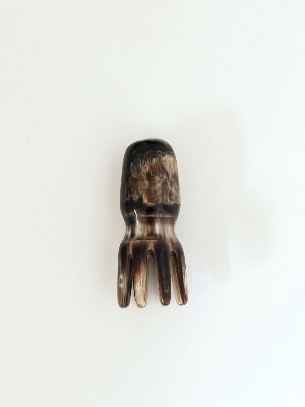 A small, dark brown object shaped like an octopus with four short legs, part of the unique Friday Five collection, displayed on a plain white background.