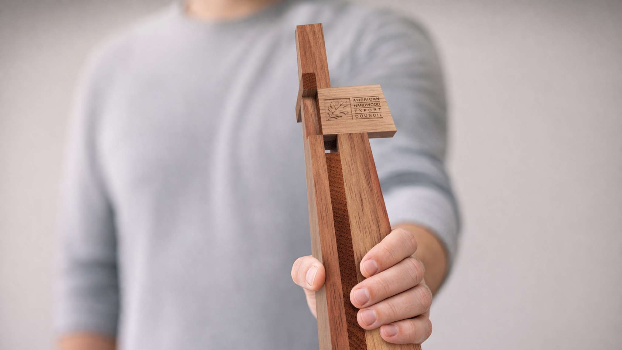 A person holds a wooden award plaque labeled 