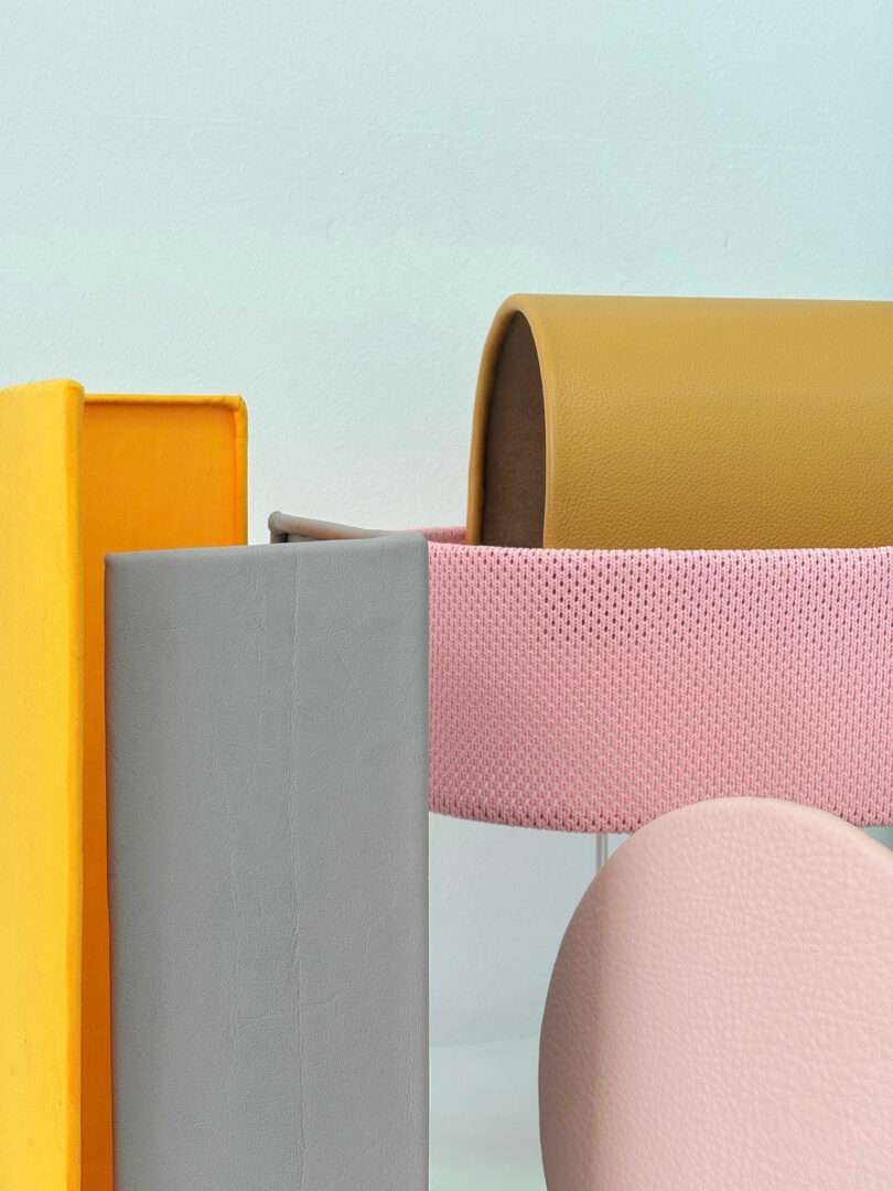 Assorted geometric shapes in yellow, gray, pink, and tan materials are arranged against a light blue background.