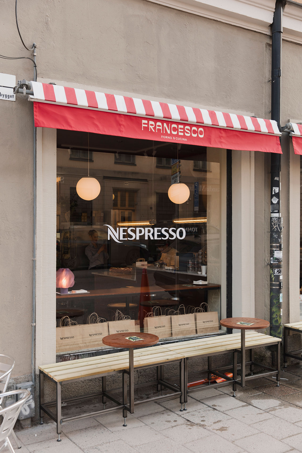 Street view of a café with a red and white striped awning labeled