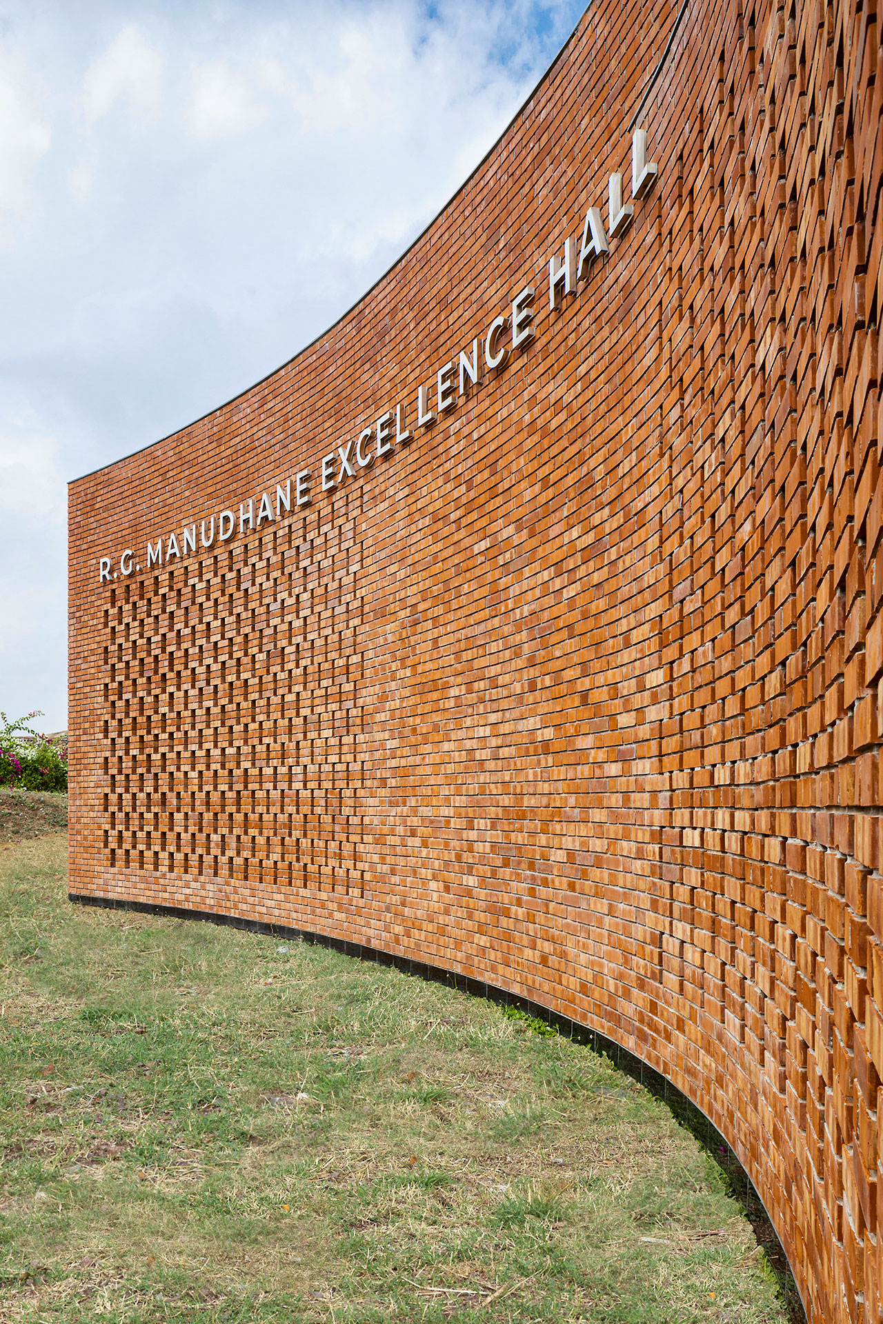 Curved brick wall designed with a touch of Morphogenesis, featuring the text 
