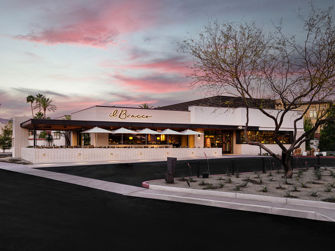 A modern restaurant with outdoor seating and a sign reading 