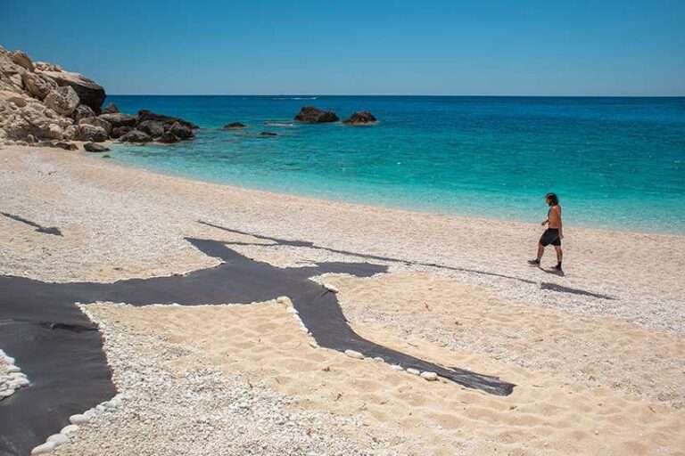 land art turns a greek beach into a scene of ancient hunters and modern extraction