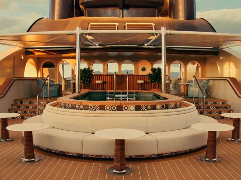 Luxury yacht deck with a round pool, curved sofa seating, white tables, tiled steps, and decorative plants in the background.