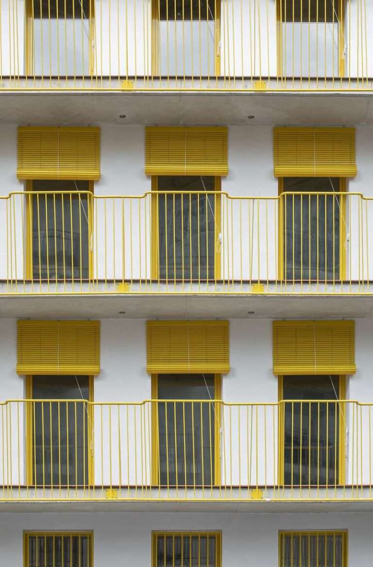 yellow steel, concrete, and circular openings revive corner building in spain as apart-hotel