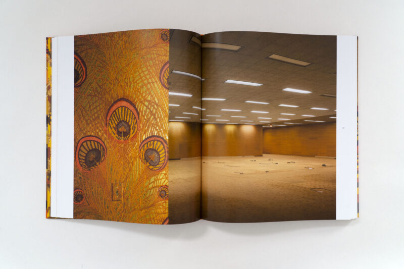An open book displaying an 820 Ebony/Jet peacock-feather pattern on the left page and an empty office interior on the right.
