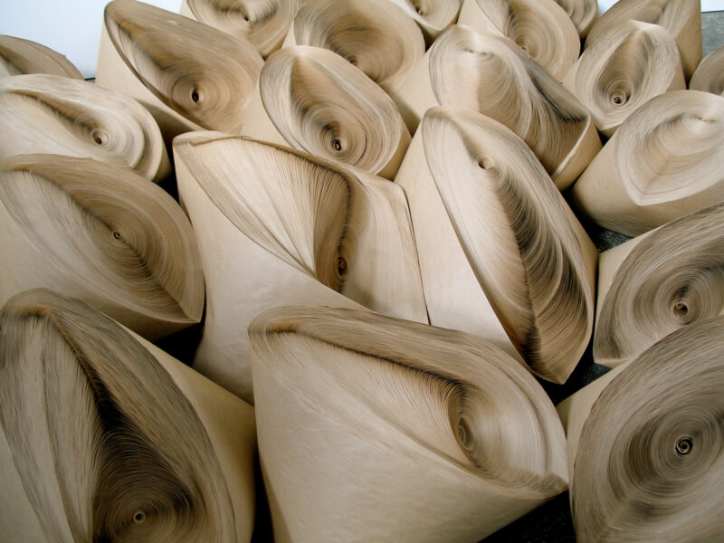 A collection of Jae Ko sculptures made from tightly coiled, stacked layers of light brown paper.